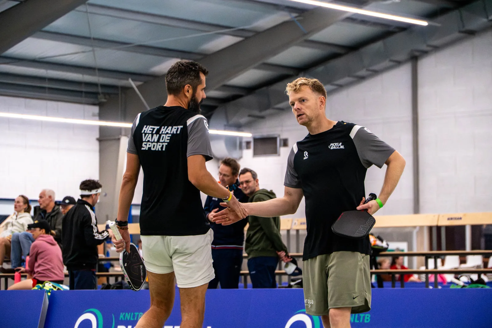 Twee spelers geven elkaar een hand na een pickleballwedstrijd op een toernooi van Pickleball.be
