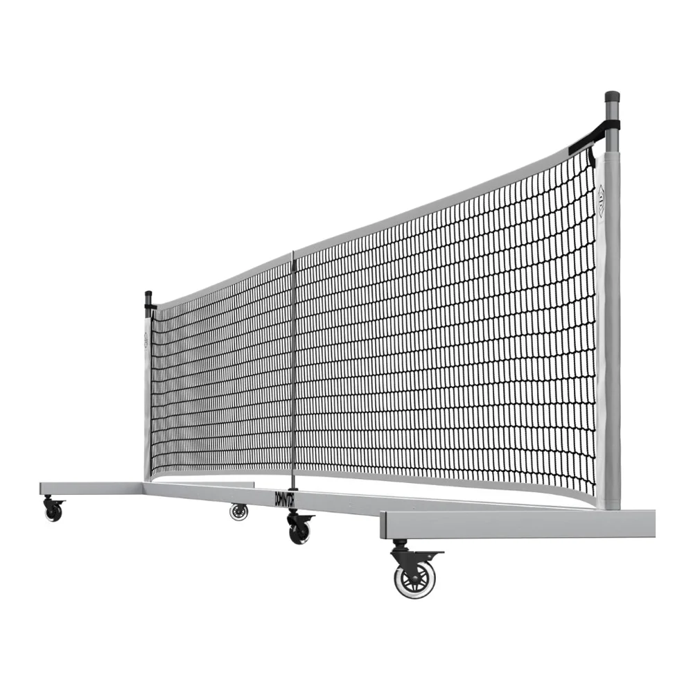 Afbeelding van een opgesteld Dominator draagbaar pickleballnet met wielen op een sportveld, klaar voor gebruik.